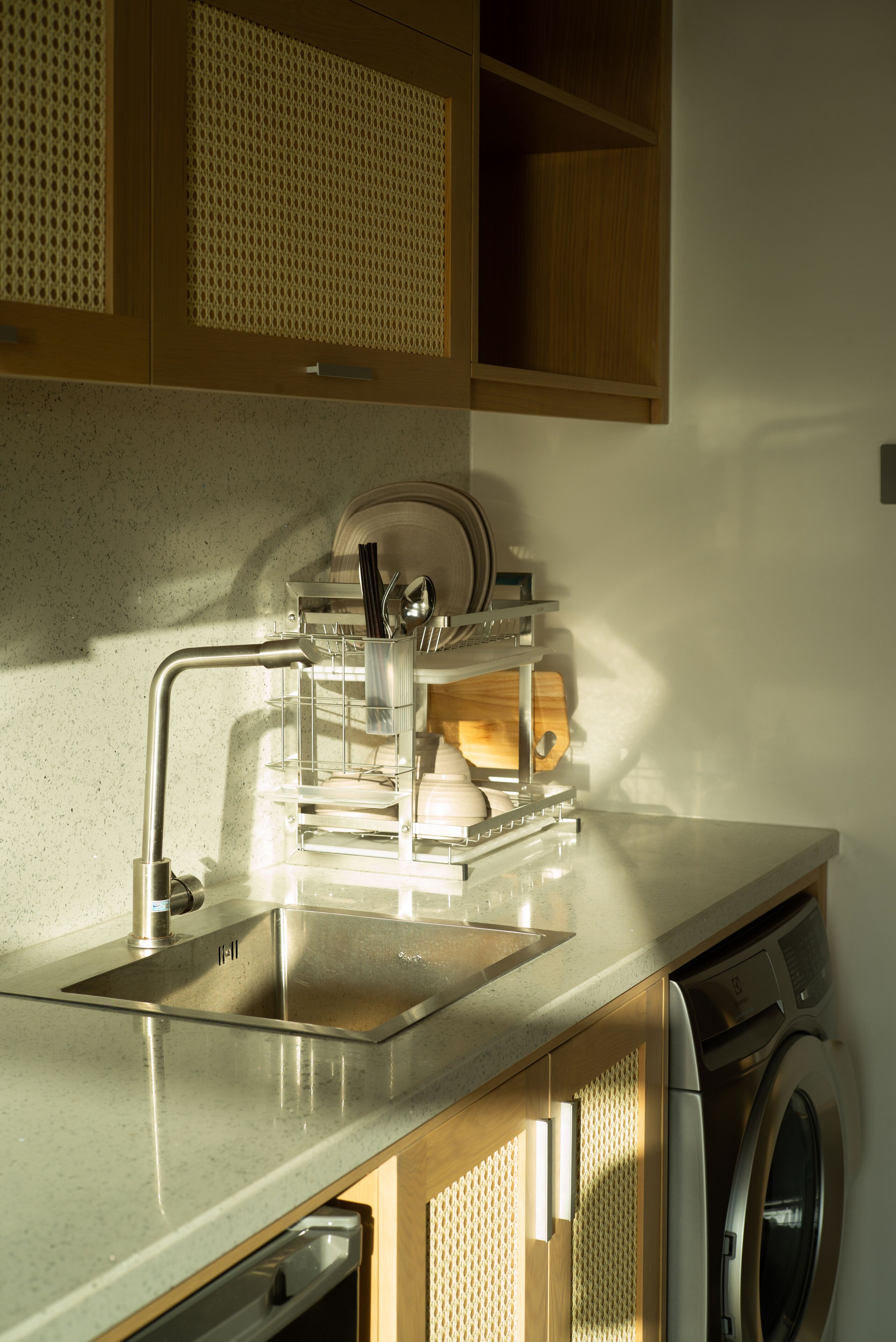 A kitchen with a stainless steel sink, a dish rack, and a built-in washing machine.