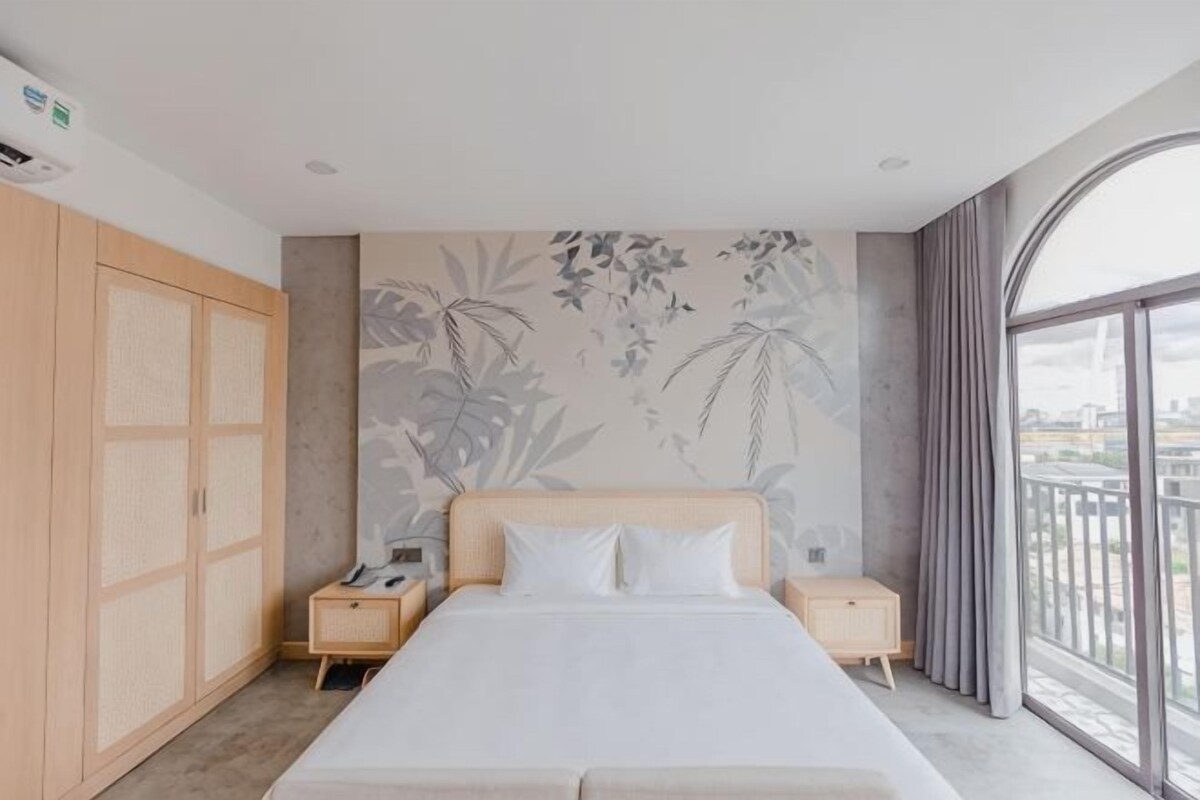 A hotel room with a bed, a nightstand, a wardrobe, and a large window with a view.