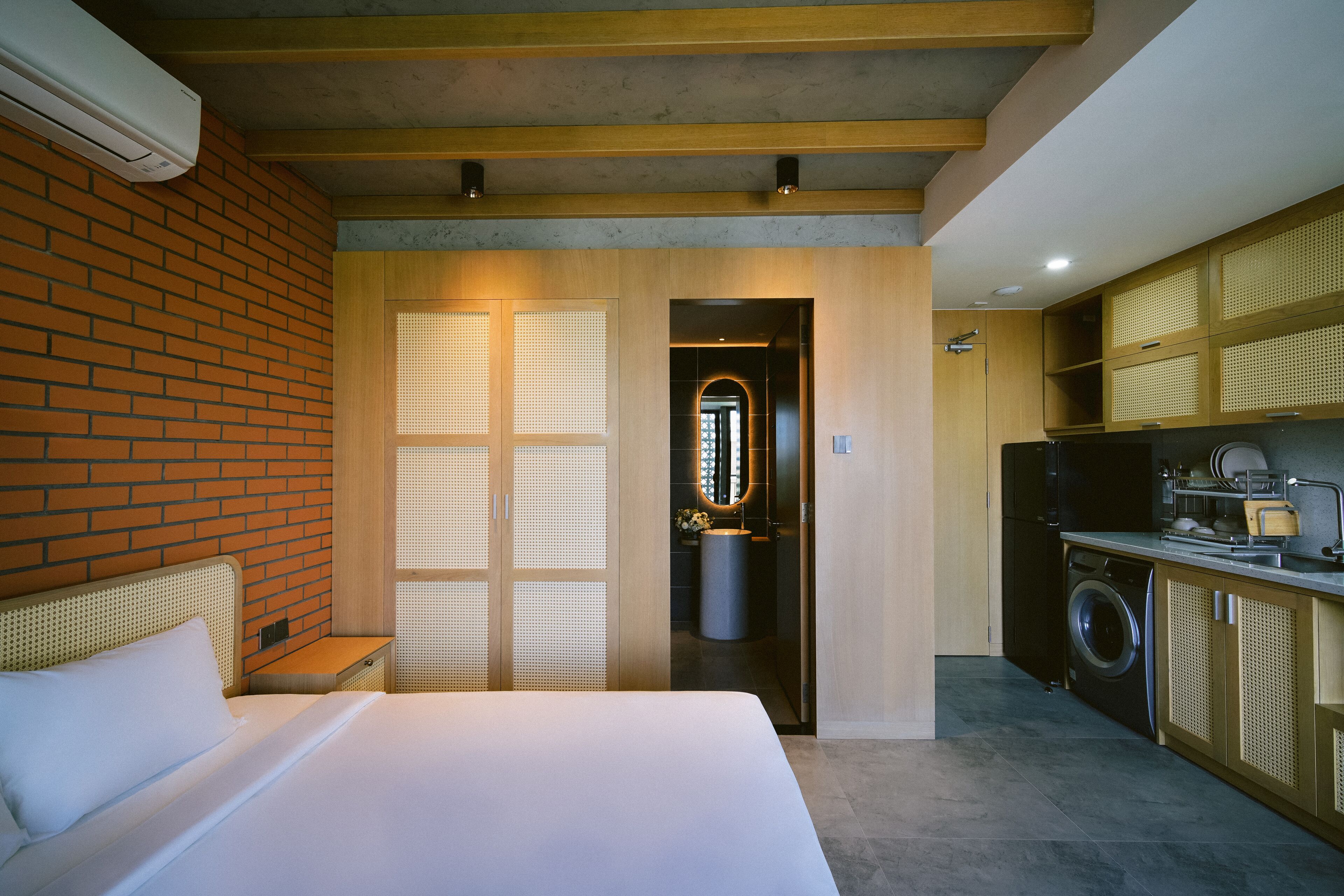 Una habitación de hotel moderna con una cama grande, un baño pequeño y una kitchenette.