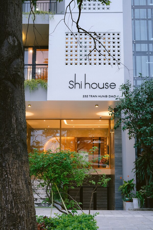 Un edificio moderno con un letrero que dice "shi house" y "232 Tran Hung Dao".