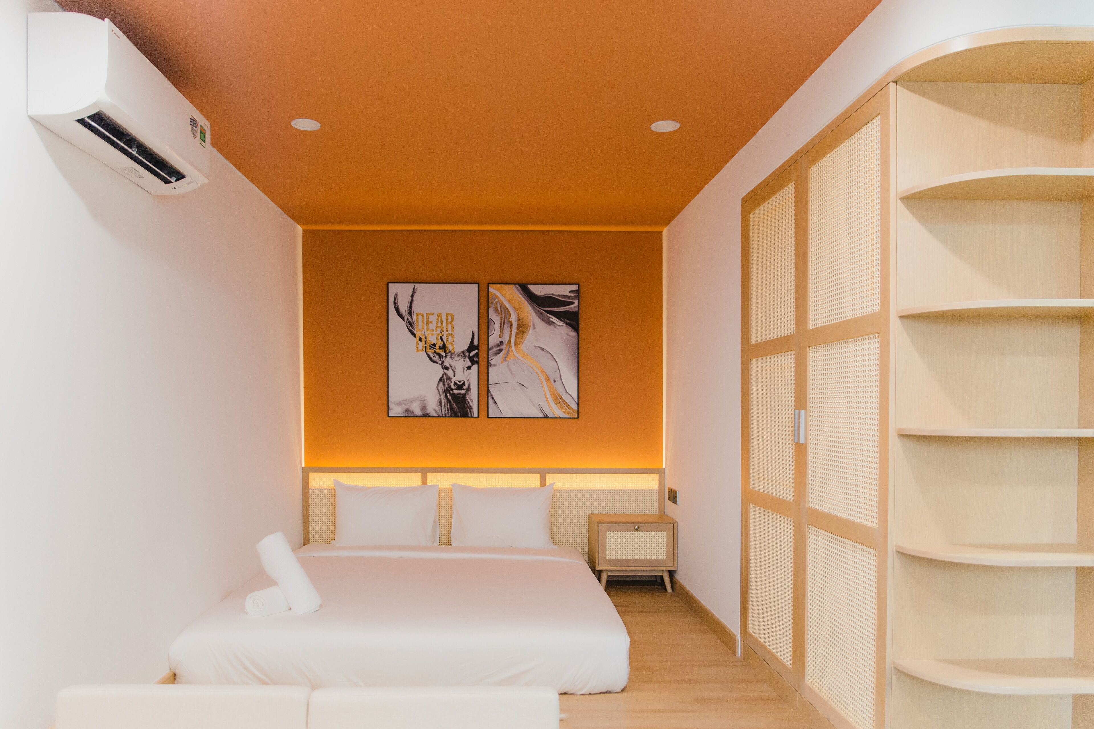 Une chambre d’hôtel moderne équipée d’un lit, d’une table de chevet et d’un climatiseur fixé au mur.