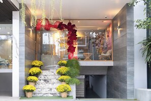 Una entrada de edificio moderna con escaleras, plantas en macetas y decoraciones colgantes.
