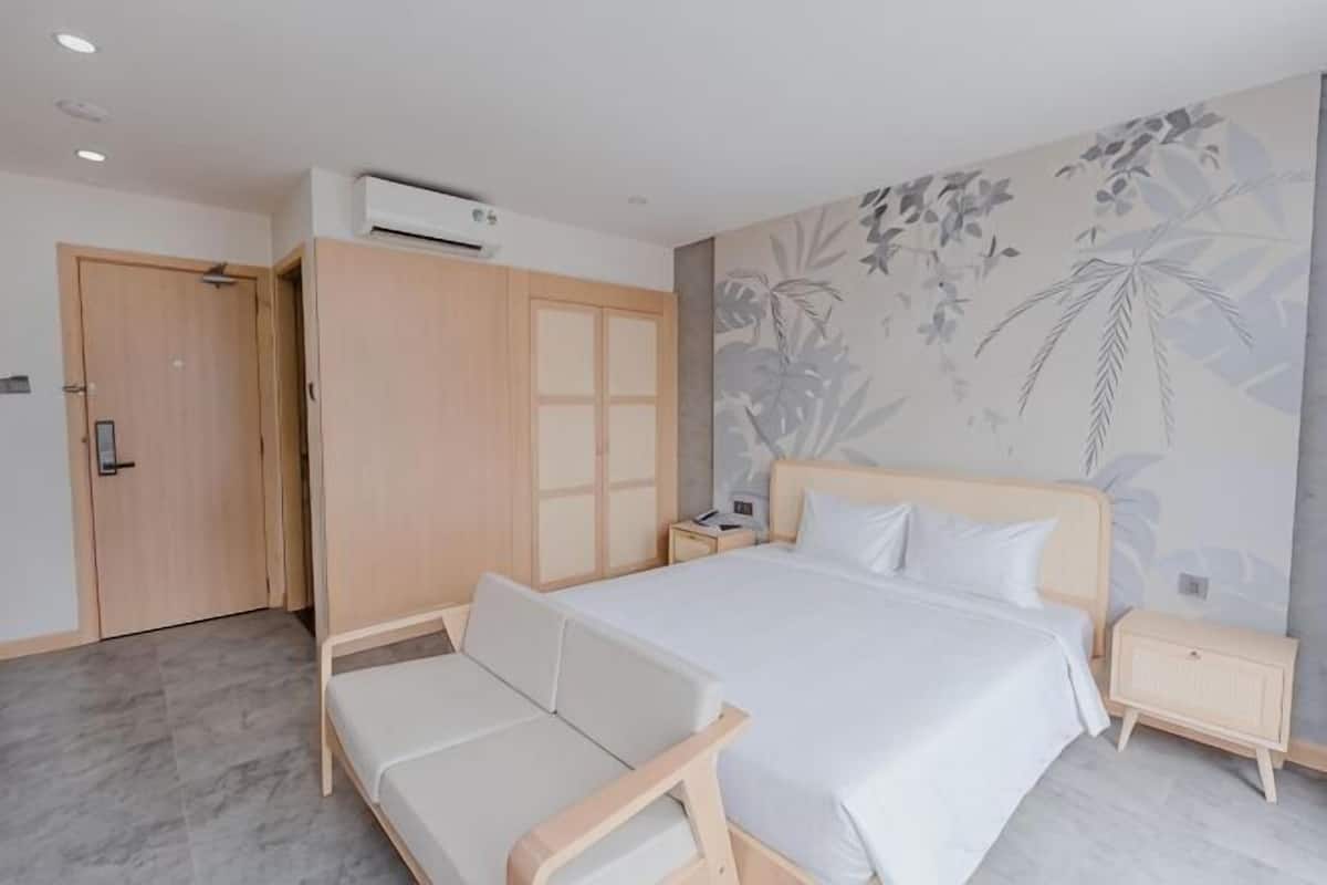 A bedroom with a bed, a sofa, a wardrobe, a nightstand, and a wall with a floral pattern.