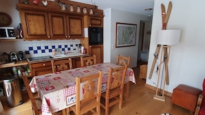 A cozy kitchen with wooden cabinets, a dining table with a checkered tablecloth, and a rustic lamp.
