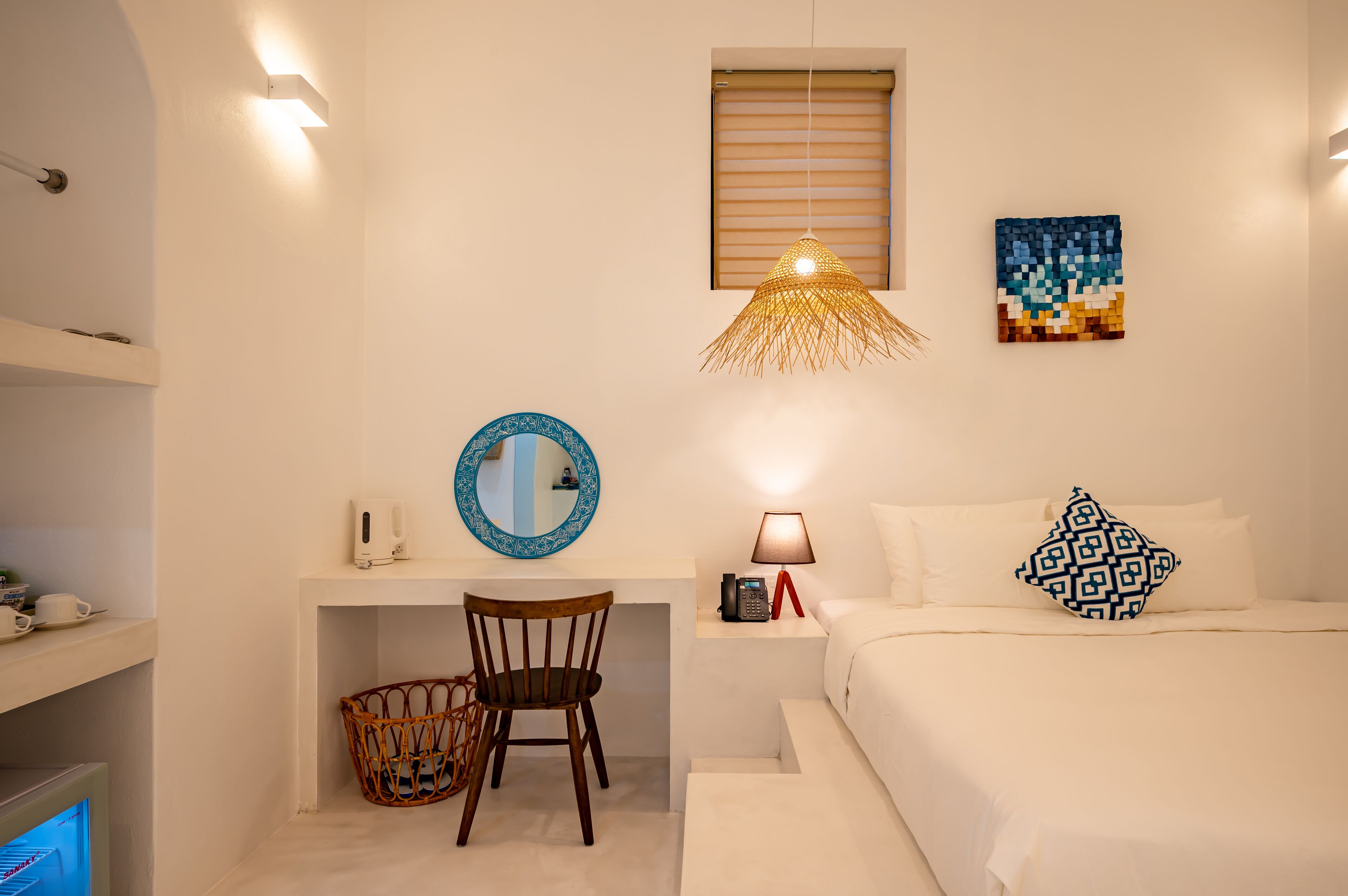 A bedroom with a bed, bedside table, lamp, and wall art.