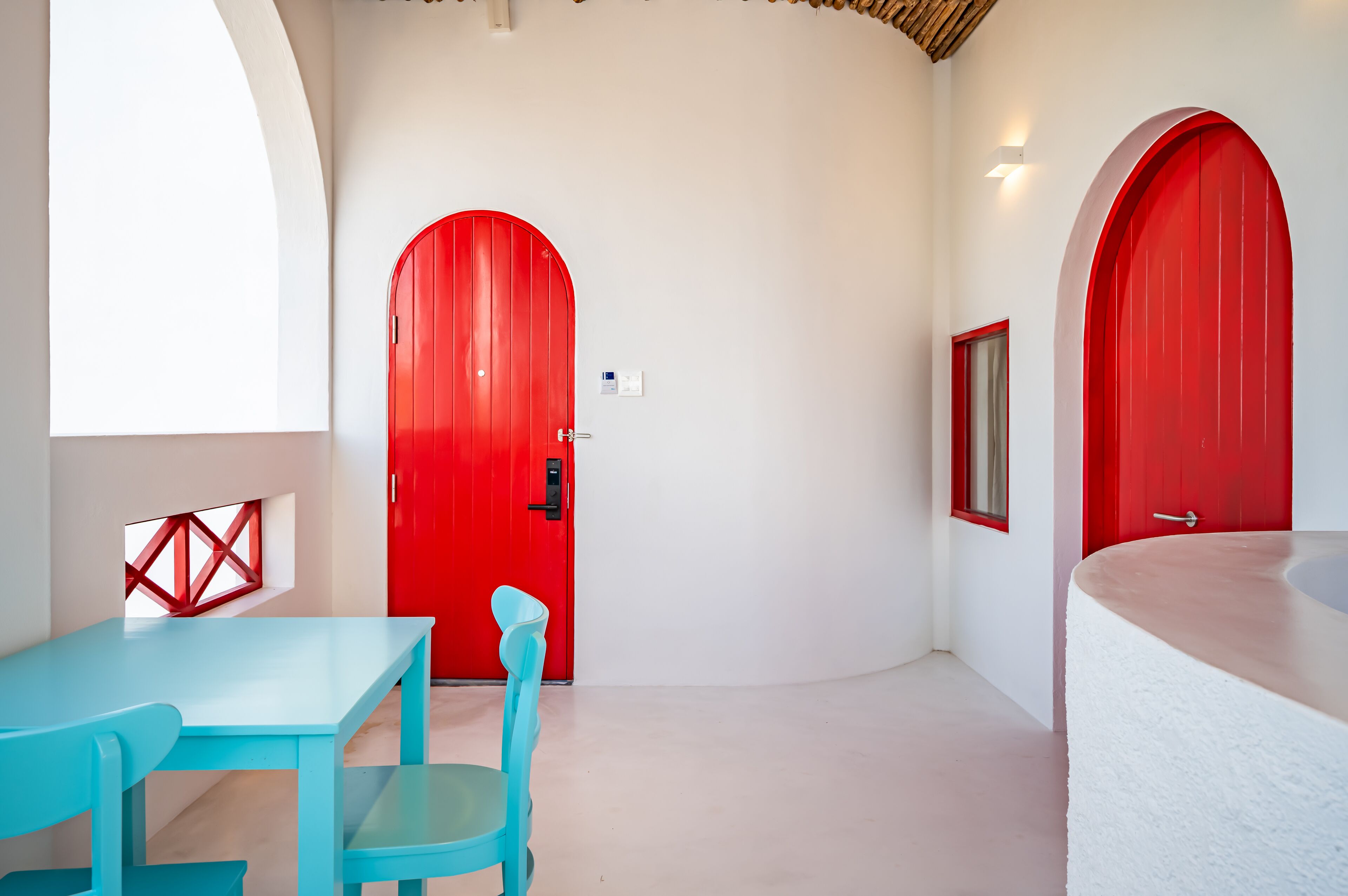 A room with a red door, a blue table, and a white bathtub.
