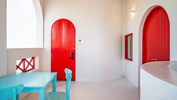 A room with a red door, a blue table, and a white bathtub.