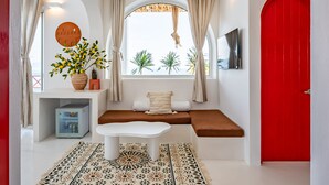 A modern interior with a white bench, a red door, and a window with curtains. - Happiness Hotel (Quy Nhon Dong)
