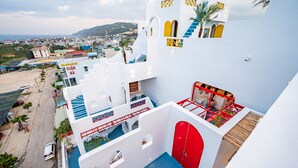 A white building with red accents, a staircase, and a view of the town. - Happiness Hotel (Quy Nhon Dong)