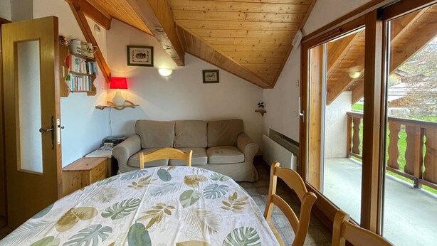 A cozy attic bedroom with a wooden ceiling, a bed with a leaf-patterned bedspread, a sofa, and a balcony with a wooden railing. - Ski-in/Ski-out, Sleeps 6, 3 Rooms, Balcony, Parking, Crest-Voland (Crest-Voland)