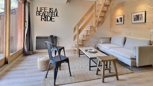 Una sala de estar moderna con una escalera de madera, un sofá, una mesa de centro y una pared con una cita motivacional.