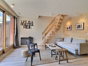 Una sala de estar moderna con una escalera de madera, un sofá, una mesa de centro y una pared con una cita motivacional.