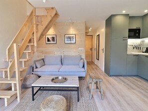 Un salon moderne avec un canapé, une table basse et un escalier.