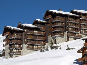 A multi-story hotel with balconies, set against a snowy backdrop. - Superb Renovated Duplex - Ski-in/Ski-out - Pets Allowed (Méribel)