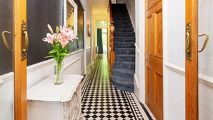 Ein Flur mit Schachbrettfußboden, einer Treppe und einem Blumenstrauß auf einem Tisch.