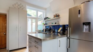 Eine moderne Küche mit einem Edelstahl-Kühlschrank, einem integrierten Wasserspender und einem Fenster für natürliches Licht.