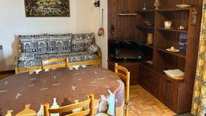 Una sala acogedora con un sofá estampado, un televisor y un mueble de madera con estantes.