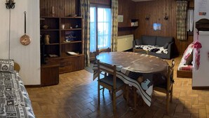 Un salón acogedor con suelo de madera, una mesa de comedor redonda, un sofá y una estantería.