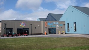 Un bâtiment sur lequel on peut lire l’inscription « Nagez, détendez-vous, amusez-vous et profitez-en », avec une entrée menant à la piscine.