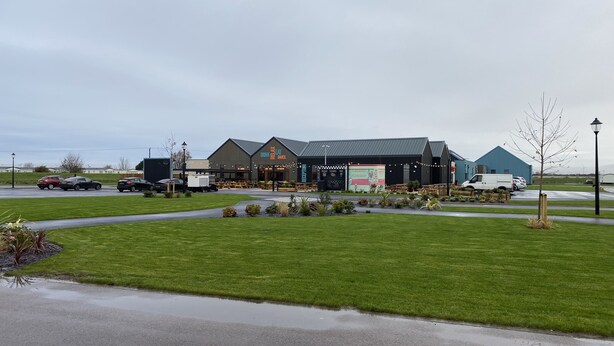 Un bâtiment sur lequel est apposée une grande enseigne indiquant « Restaurant » et une zone de stationnement où se trouvent plusieurs voitures et un camion.