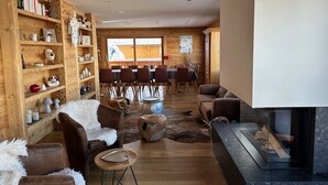 A cozy living room with a fireplace, wooden shelves, and a dining area.