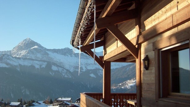 A wooden building with a balcony overlooking a snowy mountain.