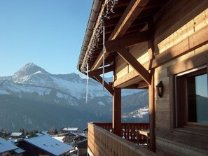 Ein Holzbalkon bietet Blick auf einen verschneiten Berg.