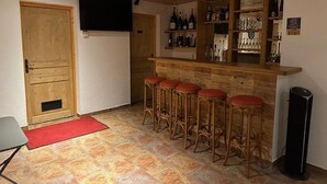 A bar area with stools, a wooden counter, and shelves of bottles.