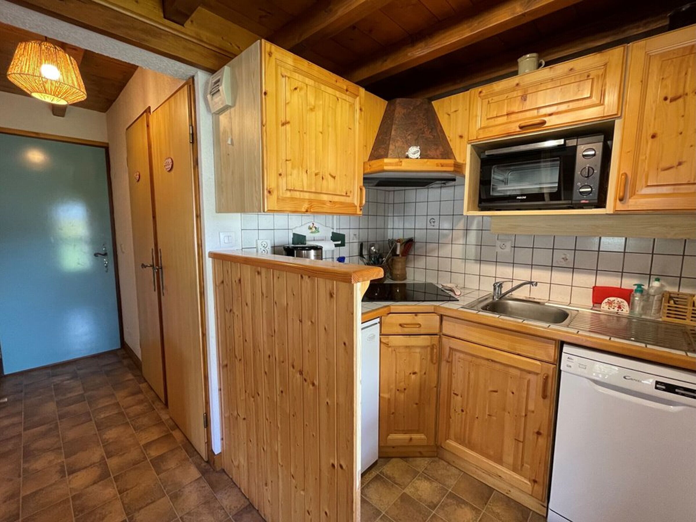 A compact kitchen with wooden cabinets, a microwave, a dishwasher, and a sink.