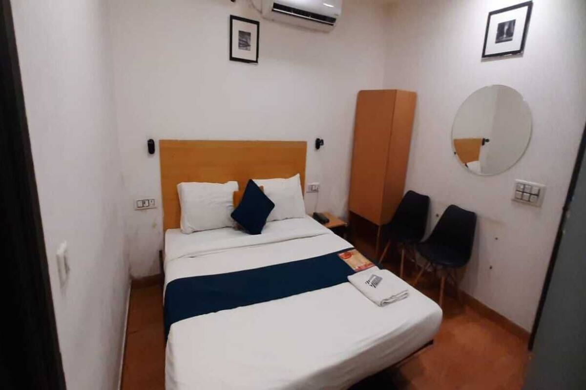 Ett hotellrum med en säng, en spegel, en garderob och en stol.