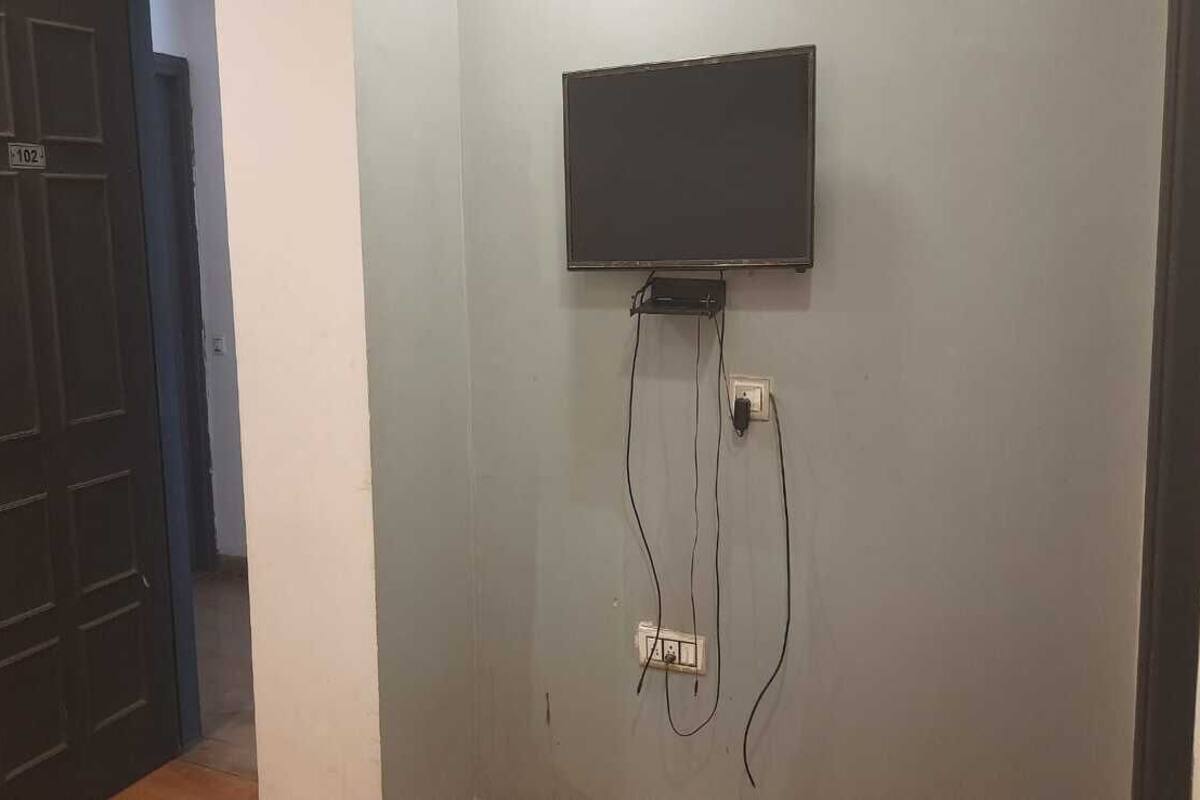 Ett rum med en platt-TV som är monterad på väggen och ansluten till ett eluttag.