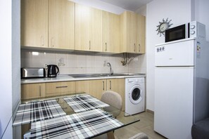 Een koelkast, een microgolfoven, kookgerei, borden en bestek