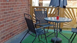 A patio with a round table, two chairs, and a small umbrella. - Apartment - Sleeps 5, Sun Terrace (Skegness)
