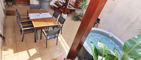 A patio area with a wooden table and chairs, potted plants, and a hot tub.