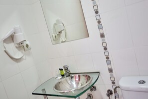 Bathroom features a glass-top sink, toilet, and wall-mounted hairdryer.