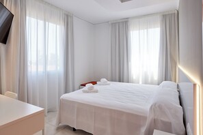 Relax in a stylish room with a neatly made bed, flat-screen TV, and desk area.