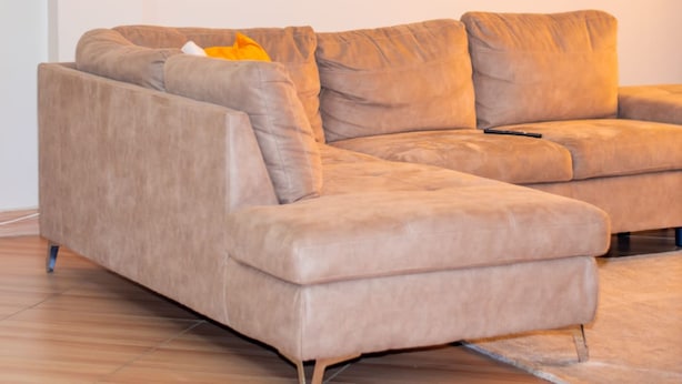 A beige sectional sofa with a remote control on it. - Affordable Heaven by CHH (Nairobi)