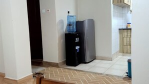 A kitchen with a refrigerator, water dispenser, and wooden cabinets. - Affordable Heaven by CHH (Nairobi)