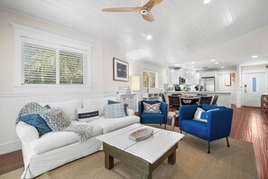 A spacious living room with a white sofa, blue armchairs, and a coffee table.