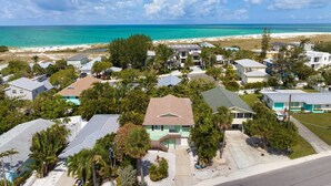 Uma área residencial costeira com casas, algumas delas com painéis solares, e uma praia ao fundo.
