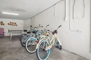 A parking area with bicycles, a table, and a wall with pipes.