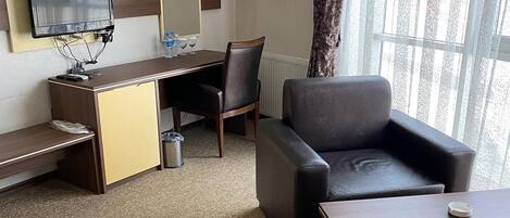 Una camera d'albergo con scrivania, sedia, divano e televisore.