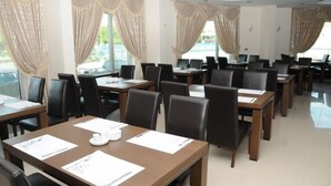A hotel conference room with multiple tables and chairs, large windows with curtains, and a modern ceiling design. - ABDULLAH RESORT OTEL (Polatli)