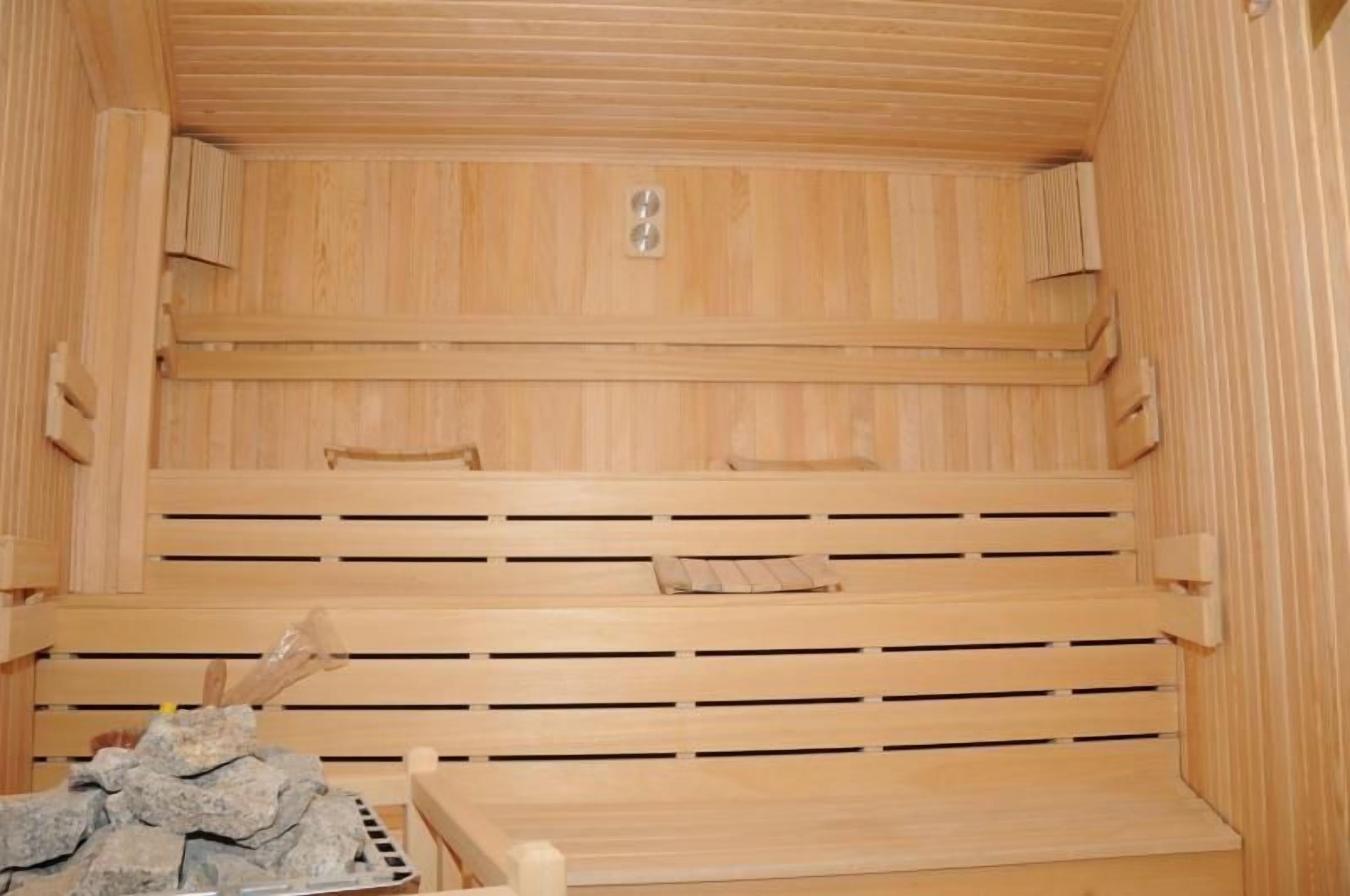 Una sauna de madera con bancos y un banco de piedra.