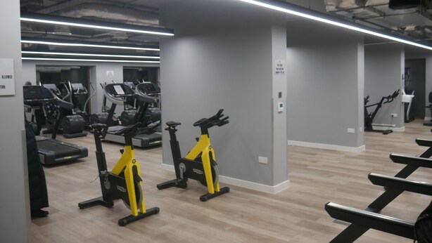 A gym with exercise equipment, including treadmills and stationary bikes, and a wooden floor. - Stunning 1-bed Apartment in London (London)