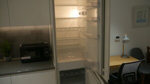 A modern kitchen with a built-in refrigerator, a microwave, and a small potted plant on the counter. - Stunning 1-bed Apartment in London (London)