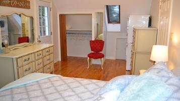 A bedroom with a bed, dresser, mirror, closet, and a red chair.