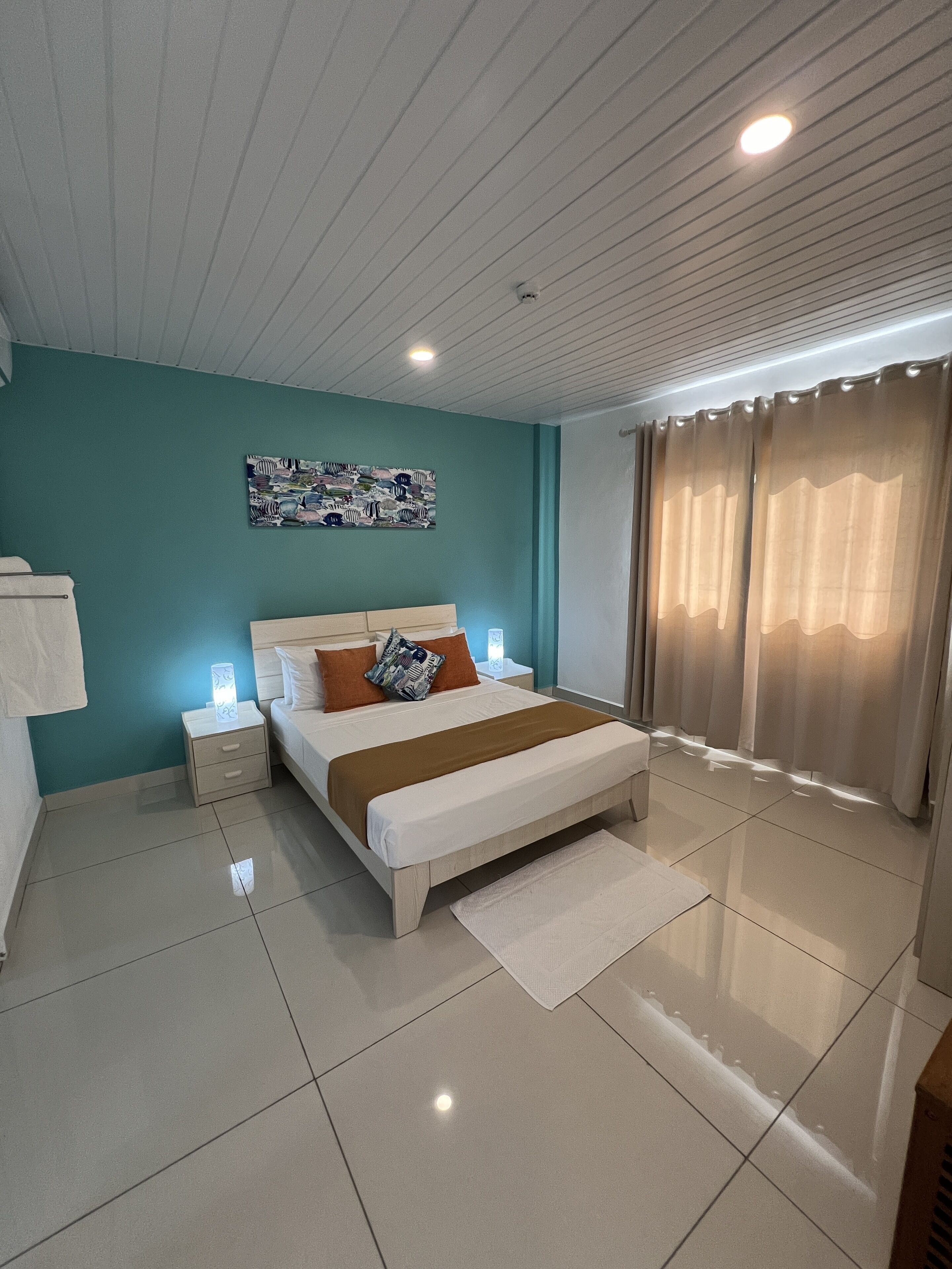 Una camera da letto moderna con un letto grande, un comodino, un'opera d'arte appesa al muro e una finestra con tende.