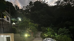 Un SUV blanco estacionado en una entrada de casa con una escalera que sube a un balcón.