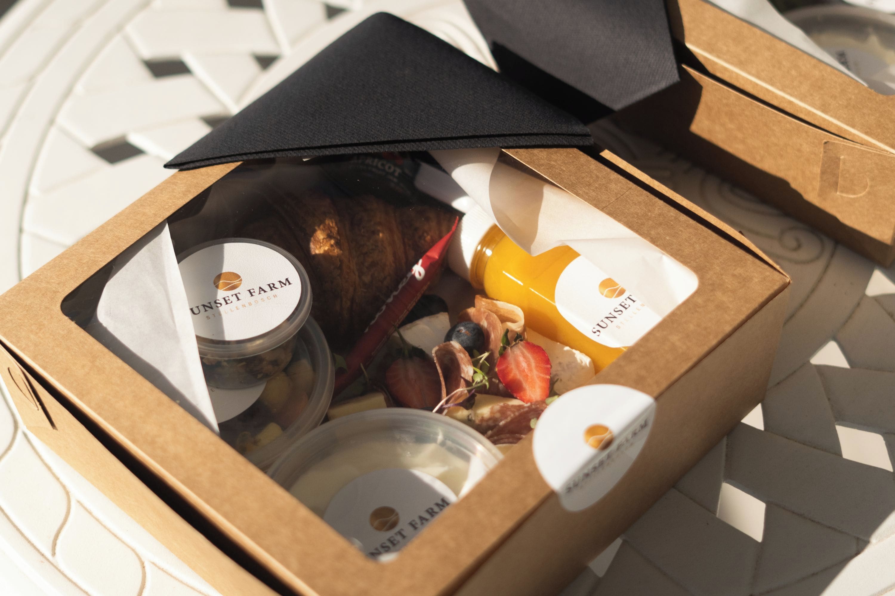 A box with a lid open, revealing a variety of food items and a candle.
